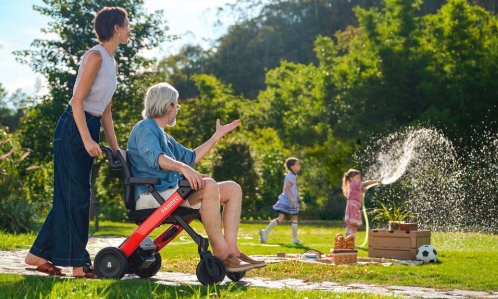 Family pushes electric wheelchair in park