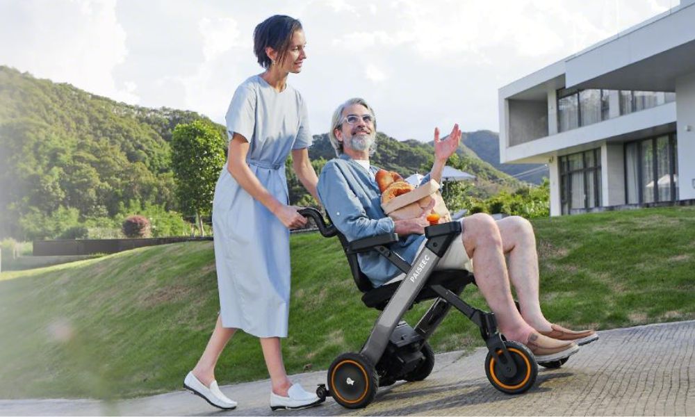 Lady pushes 4-wheel electric wheelchair uphill