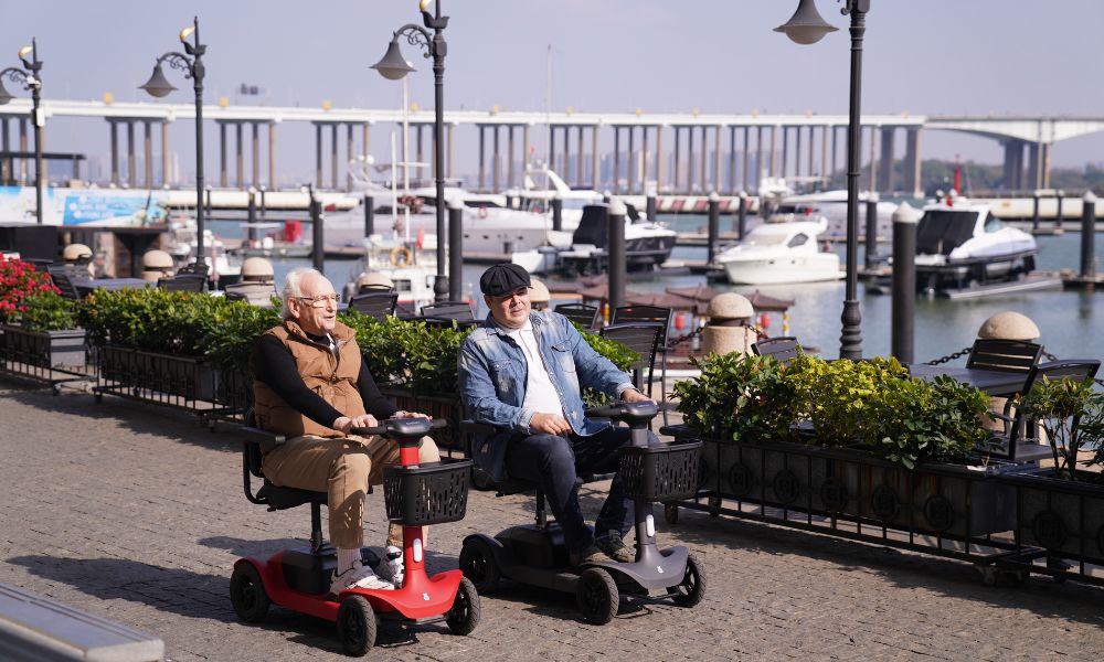 Two elderly people driving a mobility scooter on the road